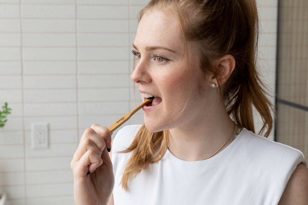 woman brushing teeth with bamboo toothbrush